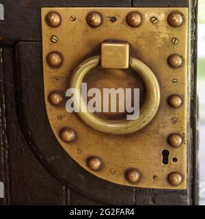 Door handle knocker selective focus on brown old wooden church entrance door front view with copyspace. Square frame Stock Photo
