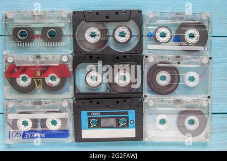 On a blue wooden background, old scratched audio cassettes lie in three rows Stock Photo