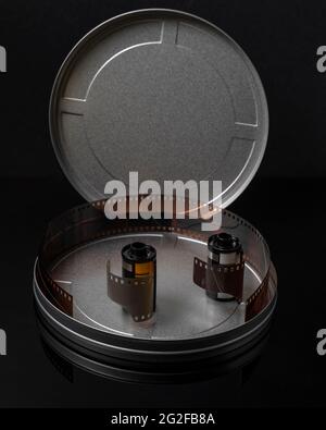 Two old rolls of analog photographic film in a circular tin container with the cap open and some negatives inside Stock Photo