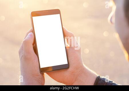 Mobile Phone outdoor, close up. Mockup image blank white screen cell phone. Men hand holding texting using mobile phone outdoor. Stock Photo