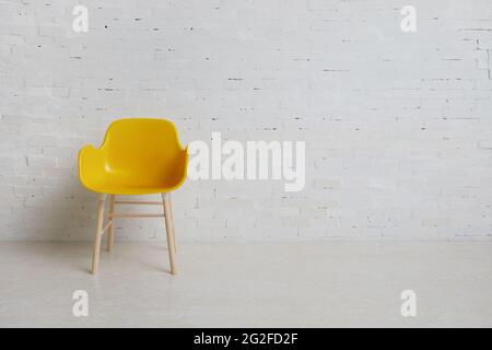 Yellow chair on the background of a white brick wall. Simple interior. Stock Photo