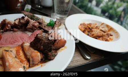 Buffet smorgasbord food on a plate sit down eating out five star casual dining red meat fish side dish of pasta pig out plethora of flavors chow down Stock Photo