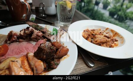 Buffet smorgasbord food on a plate sit down eating out five star casual dining red meat fish side dish of pasta pig out plethora of flavors chow down Stock Photo