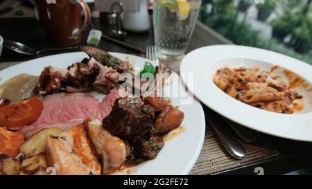 Buffet smorgasbord food on a plate sit down eating out five star casual dining red meat fish side dish of pasta pig out plethora of flavors chow down Stock Photo