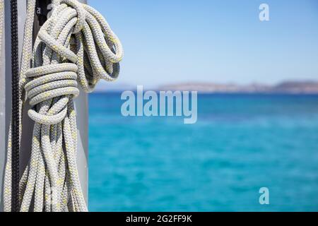 Sailboat equipment, Yachting rope tied to the ship mast. Mooring ropes on the sailing boat, blur seascape background. Closeup view, copy space. Sailbo Stock Photo