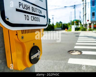 NORWALK, CT, USA - JUNE 11, 2021: Yellow box with cross button for pedestrians with  crosswalk on Post road. Stock Photo