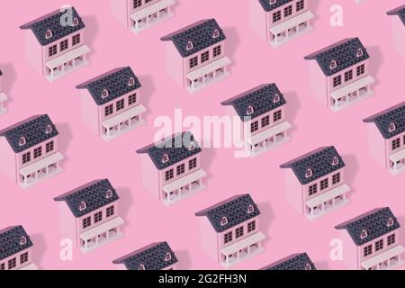 Modern pattern made with pink wooden house on a pastel pink background. Minimal creative concept. Stock Photo