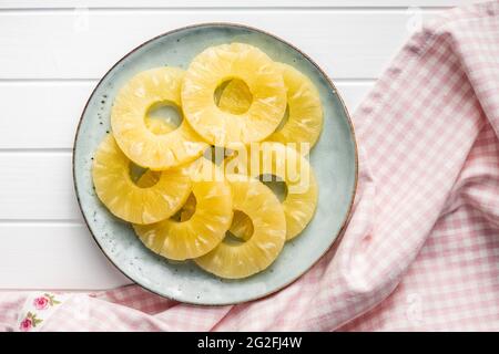Canned sliced pineapple fruit on plate. Top view. Stock Photo