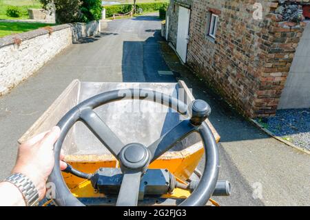 Driving a yellow mini-dump truck along a farm lane. Stock Photo