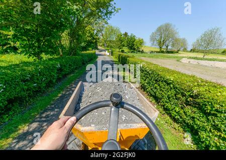 Driving a yellow mini-dump truck along a farm lane. Stock Photo