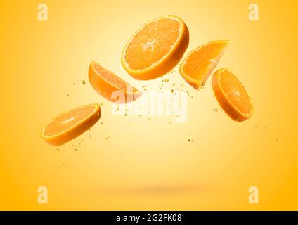 Orange fruit slices flying and dripping on colored background Stock Photo