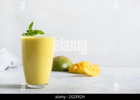 Mango lassi garnish mint on white background. Indian healthy ayurvedic drink with mango. Copy space. Freshness lassi made of yogurt, water, spices, fr Stock Photo
