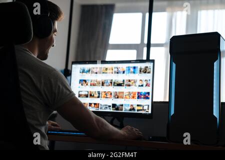 Happy brunette guy in headphones working on computer while sitting at home Stock Photo