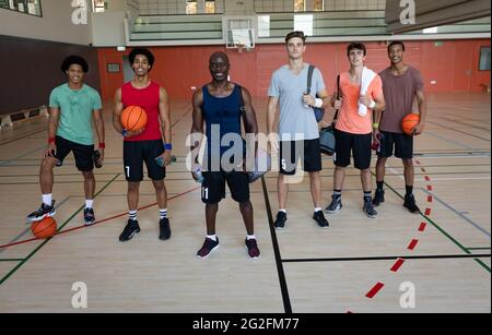 Portrait of diverse male basketball team and coach smiling and holding balls Stock Photo