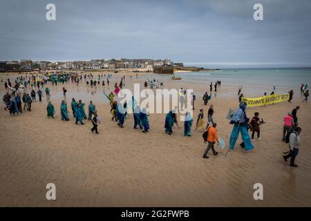 St Ives, UK. 11th June, 2021. Hundreds of protesters march across St Ives beach near where delegates are meeting for the 47th G7. Extinction Rebellion organised the demonstration to coincide with the G7-Summit. The event sees world leaders come together to discuss matters around climate change. Credit: Andy Barton/Alamy Live News Stock Photo