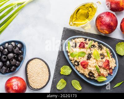 Salad with quinoa, red orange, black olives, green onion, mint and olive oil on gray concrete backkground. Vegan food. Top view or flat lay. Copy space. Stock Photo