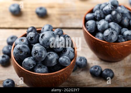 Freshly picked blueberries in clay bowl on wooden background. Concept of healthy and dieting eating. Tasty food. Stock Photo