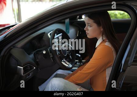 Beautiful young woman sitting in her car looking sad Stock Photo
