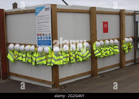 Row of hard hats and child sized high vis vests Stock Photo