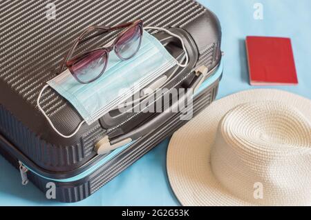 Flat lay composition with suitcase, protective mask,hat,glasses,passport, space for text. Travel concept Stock Photo