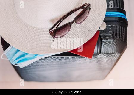 Flat lay composition with suitcase, protective mask,hat,glasses,passport, space for text. Travel concept Stock Photo