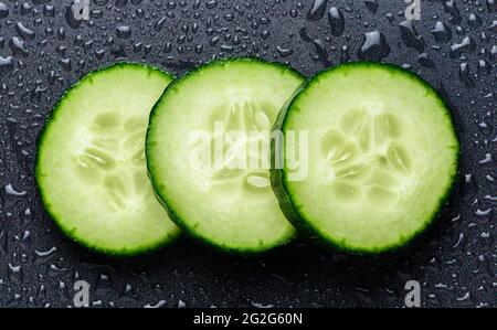 Isolated cucumber slices. Pieces of fresh cucumber isolated on black background Stock Photo