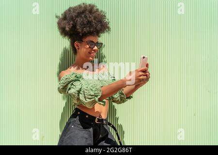 woman with afro hair sending a message from her smartphone Stock Photo
