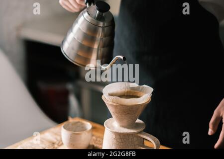 Brewing pourover coffee in the kitchen, pouring hot water on the Stock Photo