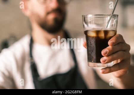 Barista holds a glass of cold brew coffee with ice