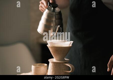 Brewing pourover coffee in the kitchen, pouring hot water on the Stock Photo