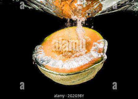 Half of Orange cantaloupe melon sinking, isolated on black Stock Photo