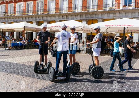 Tourists on a city tour riding on Segway. The Plaza Mayor, Main Square, is a major public space in the heart of Madrid, the capital of Spain. Madrid, Stock Photo