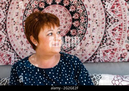 Attractive middle-aged woman with red hair looking aside. Mandala background Stock Photo