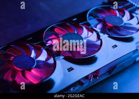 A graphics card with a row of fans with a cyanotic purple backlight in a futuristic design. Powerful gaming graphics card for video games and cryptocu Stock Photo