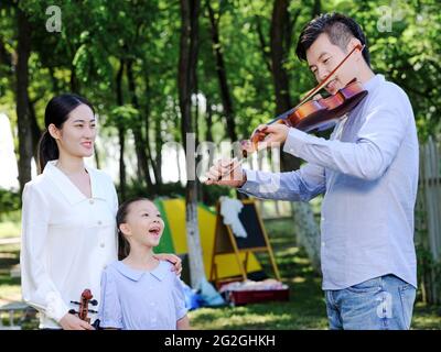 Happy family of three playing violin in the park high quality photo Stock Photo