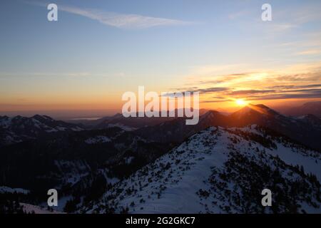 View of the frozen Soinsee, towards Wendelstein on the far left and Chiemgau with Chiemsee from the Auerspitz. sunrise between small Traithen (1722m) and large Traithen (1851m) Europe, Germany, Bavaria, Upper Bavaria, Bavarian Alps, Mangfall Mountains, Spitzingsee Stock Photo
