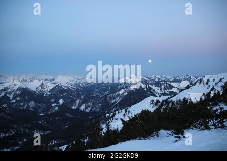 From the Auerspitze direction of the Karwendel Mountains southwest, the setting moon over the mountains from left to right Österr. Schinder 1807m, in the middle of the Risserkogel (1825m), Blankenstein (1768m), Bendiktenwand (1799m), Setzberg, Hirschberg, Wallberg, in front of that the Rotwand with the Rotwandhaus shortly before sunrise. Europe, Germany, Bavaria, Upper Bavaria, Bavarian Alps, Mangfall Mountains, Spitzingsee Stock Photo