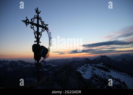 View from the Auerspitz (1811m) towards Chiemgau der Große Traithen (1851m) on the far right, the summit cross in front of the Chiemsee in anticipation of the rising sun, atmospheric, Europe, Germany, Bavaria, Upper Bavaria, Bavarian Alps, Mangfall Mountains, Spitzingsee Stock Photo