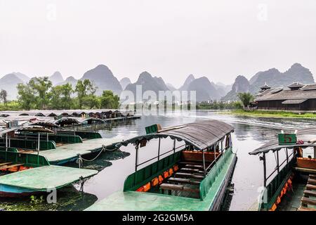 Moored cruise boats on Swallow Lake with majestic karst mountains in the background in Shangri-la Park, Guilin, China Stock Photo