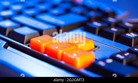 Close-up of orange arrow keys on a black keyboard, up, down, left, right buttons on a gaming computer keyboard. Stock Photo