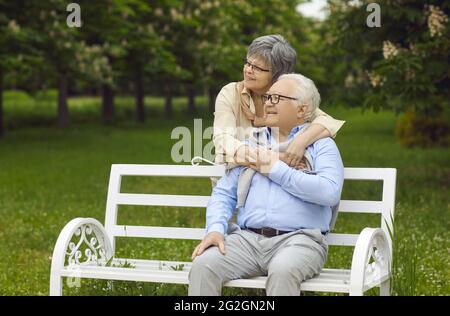 Portrait of loving senior couple hugging outdoors rest in park looking forward Stock Photo
