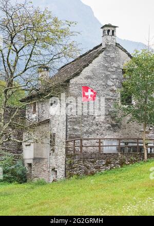 Impressions from Lavertezzo in the Verzasca Valley, Locarno district, Canton Ticino in Switzerland: popular excursion destination for hiking, river diving and swimming. Historic town center, house with the Swiss flag. Stock Photo