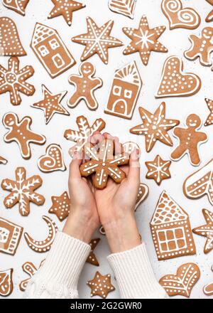 Child hands holding a homemade Christmas painted gingerbread in the form of a snowflake. Scandinavian pattern. Top view. Stock Photo