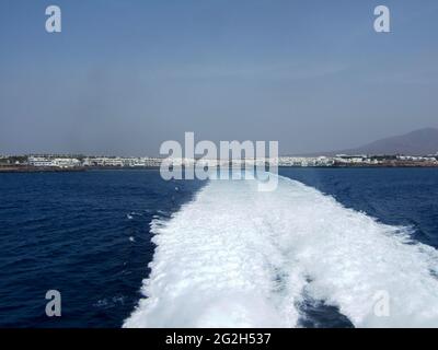 Large swirl of the tail water. View from the Fred Olsen Canary Island Ferry to the flat land of Playa Blanca Lanzarote in the haze of heat Stock Photo