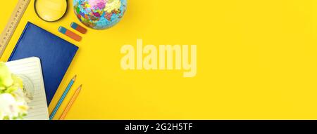 School education banner with stationery, yellow table with the globe, notebooks and pencils, copy space, top view Stock Photo