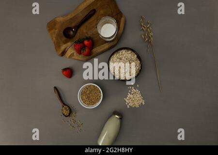 Oat milk, ear of wheat, board, strawberries, oatmeal, oat kernels, spoon, top view Stock Photo