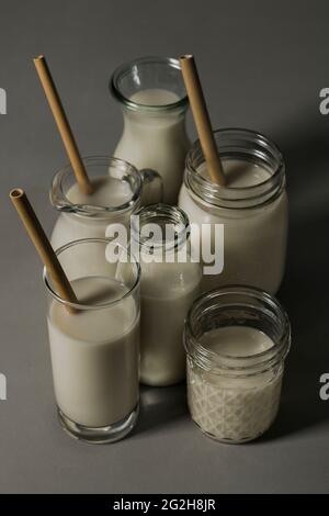 Oat milk, drinking straws, glass, carafe, mason jar, milk bottle Stock Photo