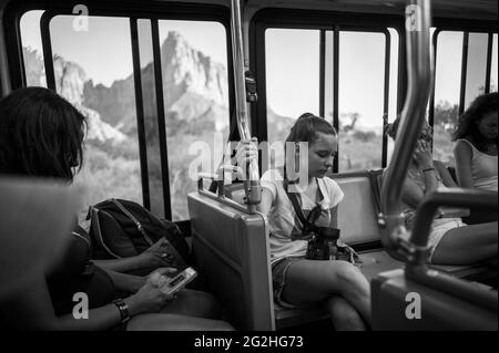A girl sitting in the Zion Canyon Shuttle Bus with a mountain in the back in Zion National Park, Utah, USA Stock Photo