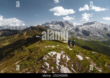 Landscape of the Prokletije National Park in bright sunshine with two hikers on a narrow beaten path Stock Photo