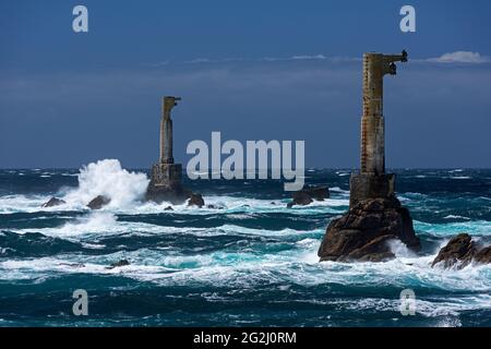 Waves crash on the rocks and the two relay towers of the Phare de Nividic at Pointe de Pern, Île d'Ouessant, France, Brittany, Finistère department Stock Photo